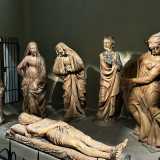Al centro giace il corpo di Cristo, disteso con il capo reclinato su un cuscino. Attorno a lui, sei personaggi immersi nel dolore partecipano al lutto con gesti e posture differenti, ognuno espressione di un sentimento unico di disperazione